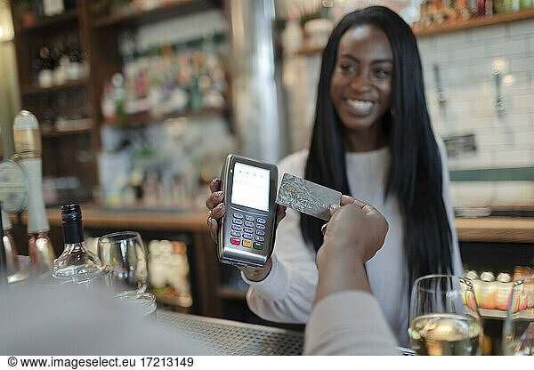 Customer paying female bartender with smart card in bar