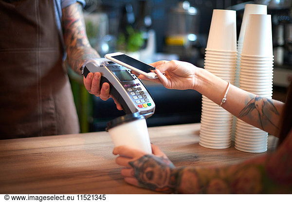 Customer paying for her coffee by mobile payment