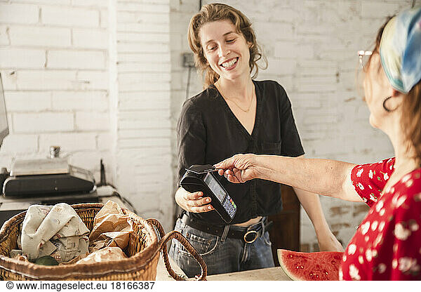 Customer paying with credit card at checkout counter in greengrocer shop