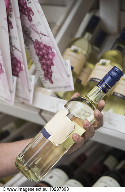 Customer reading label on a wine bottle in supermarket  Augsburg  Bavaria  Germany