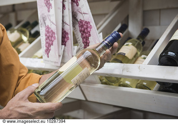 Customer reading label on a wine bottle in supermarket  Augsburg  Bavaria  Germany