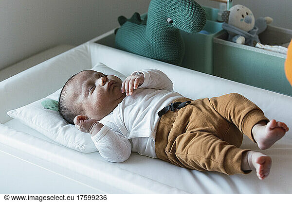 Cute baby boy lying in crib at home