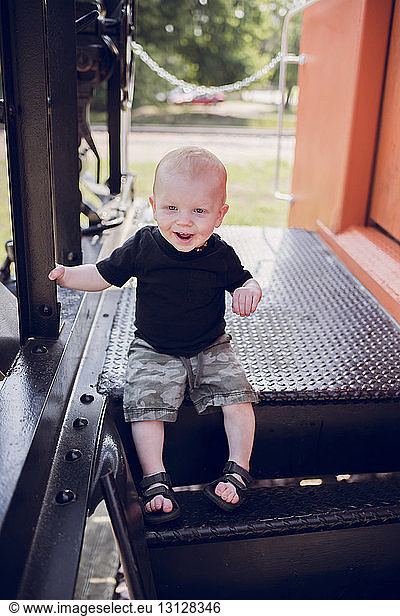 Cute baby boy sitting on outdoor play equipment at playground