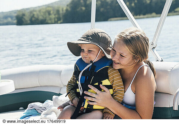 Cute baby boy sitting on womans lap on river boat
