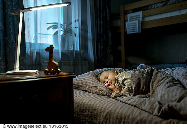 Cute baby boy sleeping on bed