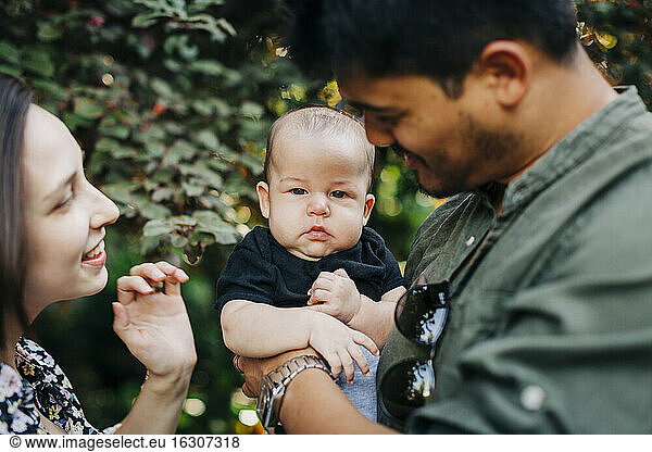 Cute baby boy with parents at park during weekend