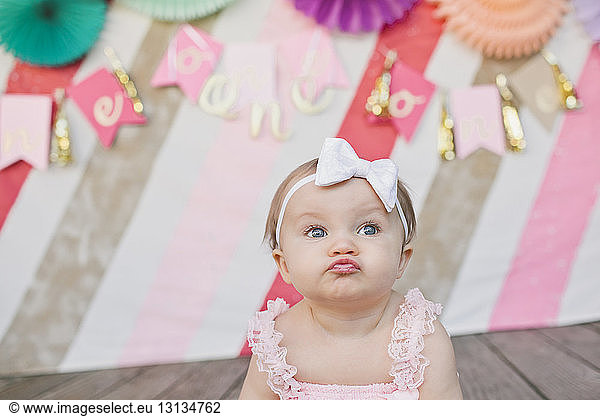 Cute baby girl puckering against decoration at her first birthday party