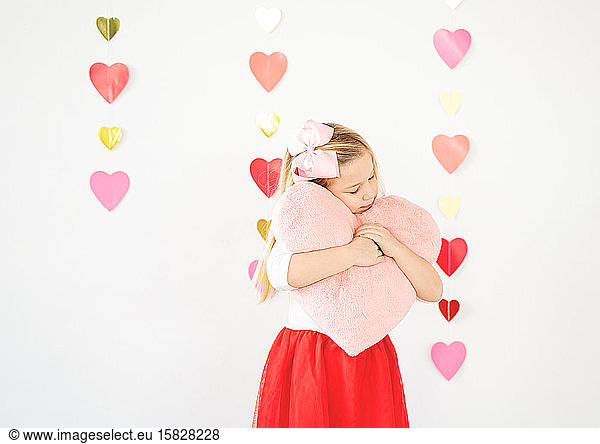 cute blond girl hugging plush pink heart valentine's day