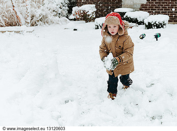 Cute boy making snowball in yard