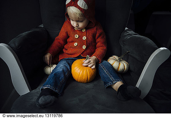 Cute boy playing with pumpkins at home during Halloween