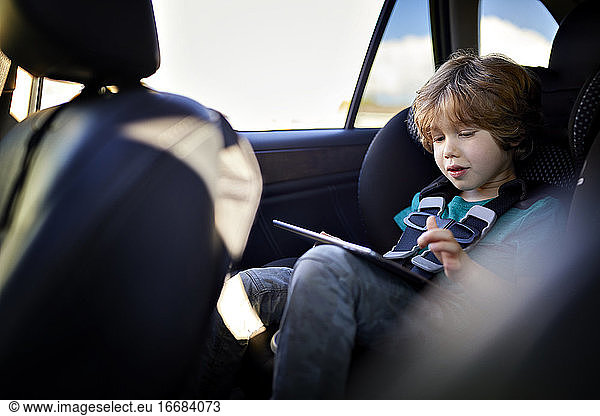Cute boy using tablet PC while traveling in car