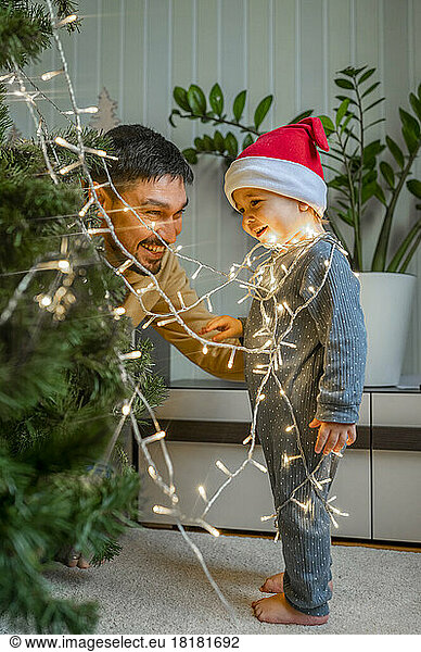 Cute boy with father decorating Christmas tree at home