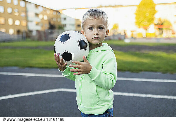 Cute boy with soccer ball in sports court
