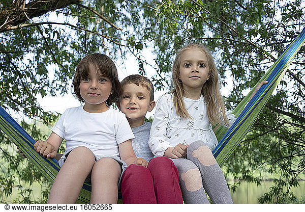 Cute children sitting on hammock in forest