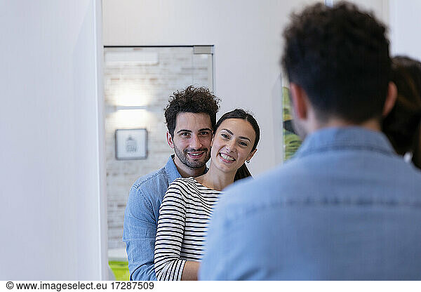 Cute couple embracing in front of the mirror at home