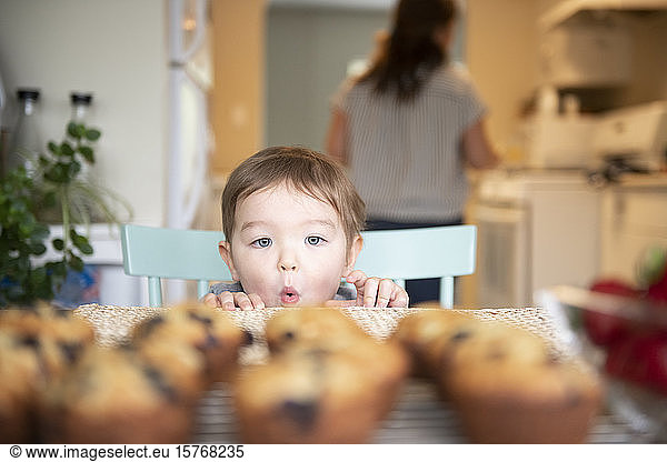 Cute excited girl starting at fresh homemade muffins