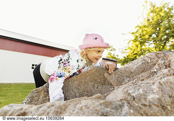 Cute girl climbing rock at field
