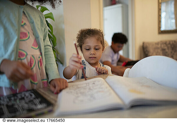 Cute girl coloring in coloring book with colored pencil