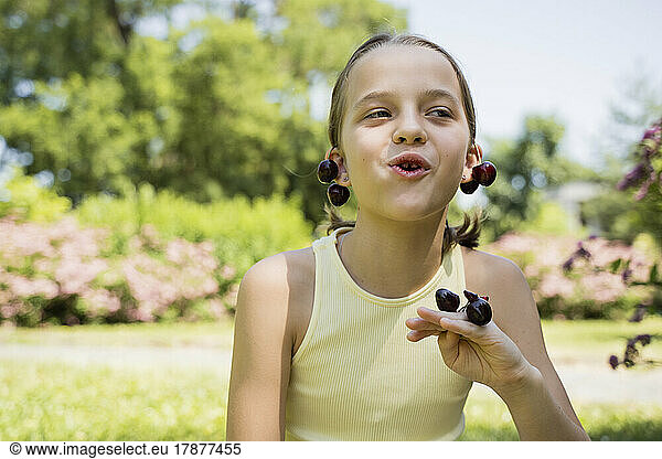 Cute girl eating cherries at park