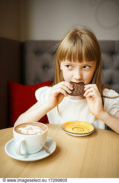 cute girl eats chocolate chip cookies and drinks cocoa with a pattern