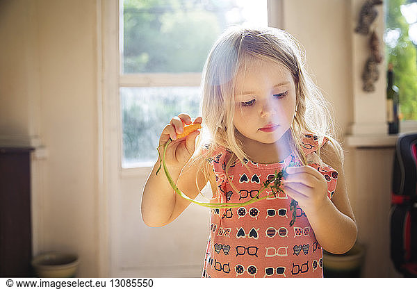 Cute girl holding carrot at home
