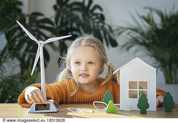 Cute girl operating wind turbine model at home