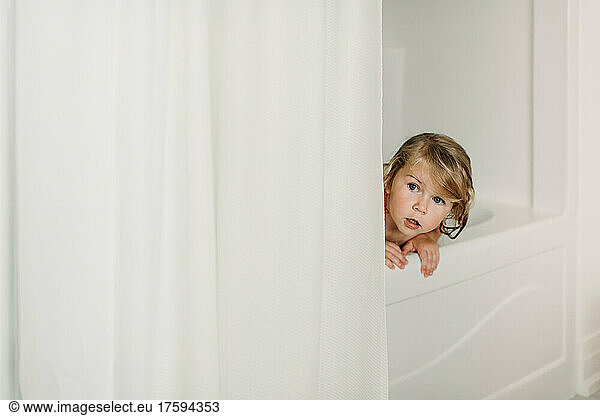 Cute girl peeking in bathtub