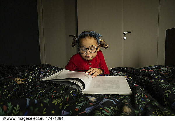 Cute girl reading book in bedroom