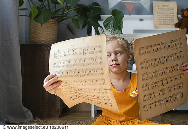 Cute girl reading musical notes at home