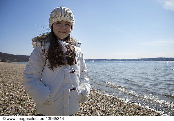 Cute girl standing at beach against sky
