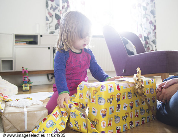 Cute girl unwrapping gift at home
