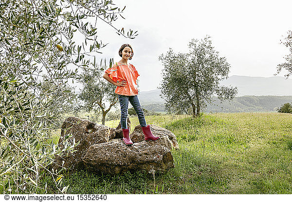 Cute girl with bobbed hair standing on rock in scenic field landscape  portrait  Citta della Pieve  Umbria  Italy