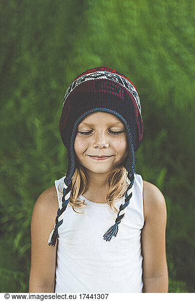 Cute girl with wearing knit hat standing with eyes closed