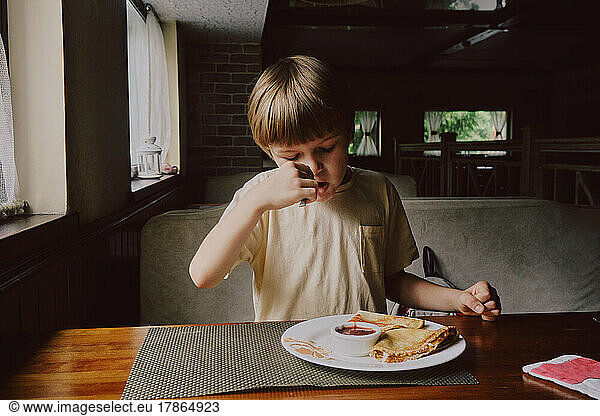 Cute healthy preschool kid boy eats in cafe.