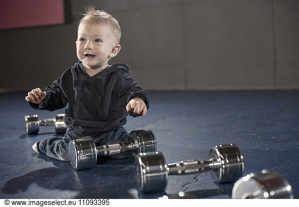 Cute little baby playing with dumbbells in gym