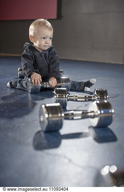 Cute little baby playing with dumbbells in gym