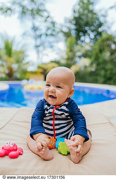 Cute Little Baby Sitting neben einem Pool spielen mit einem Spielzeug