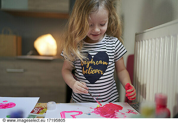 Cute little girl being creative with paint on her hands