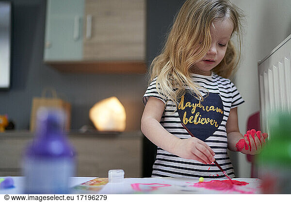 Cute little girl being creative with paint on her hands