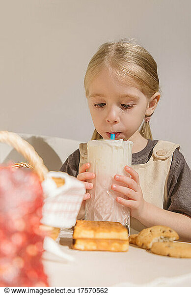 Cute little girl eating cookies with milkshake