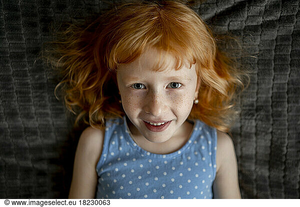 Cute redhead girl with freckles on face at home
