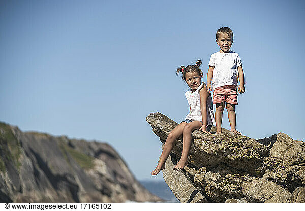 Cute sibling on flysch against blue sky