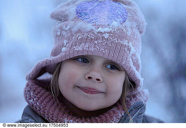 Cute smiling girl wearing knit hat with snow