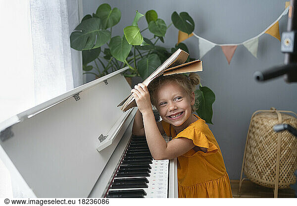 Cute smiling girl with musical notes at piano at home