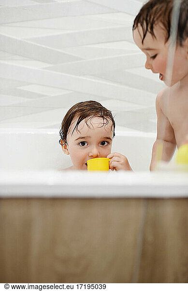 Cute twin boys taking a bath  one looking directly into camera