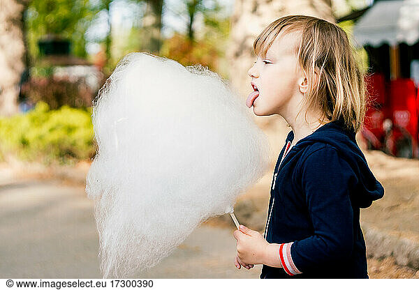 Cute young girl 3-4 years old eating cotton candy