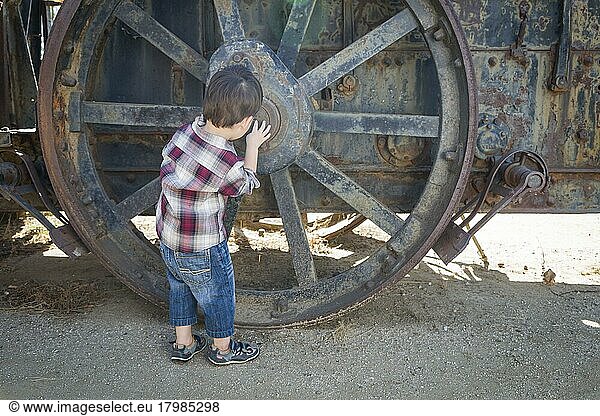 Cute young mixed-race boy having fun near antique machinery outside