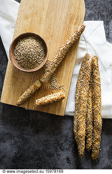 Cutting board and fresh Italian grissini breadsticks with sesame seeds