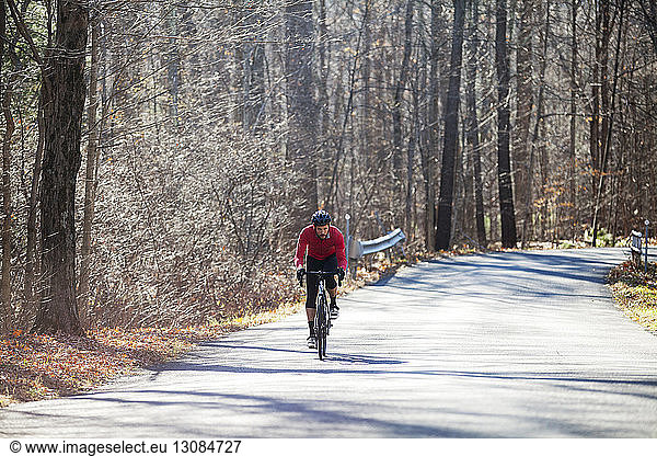 Cyclist riding bicycle on road in forest
