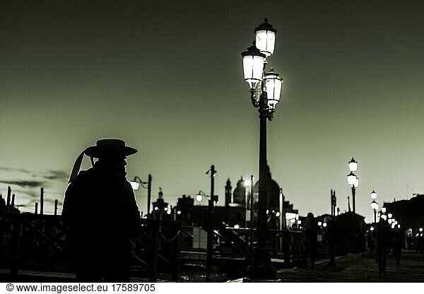 Düstere Stimmung  Gondoliere als Schattenriss bei blauer Stunde vor beleuchteter Straßenlaterne  Venedig  Venetien  Italien  Europa